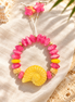 Pink beaded bracelet with yellow spiral shell and starfish cord ends