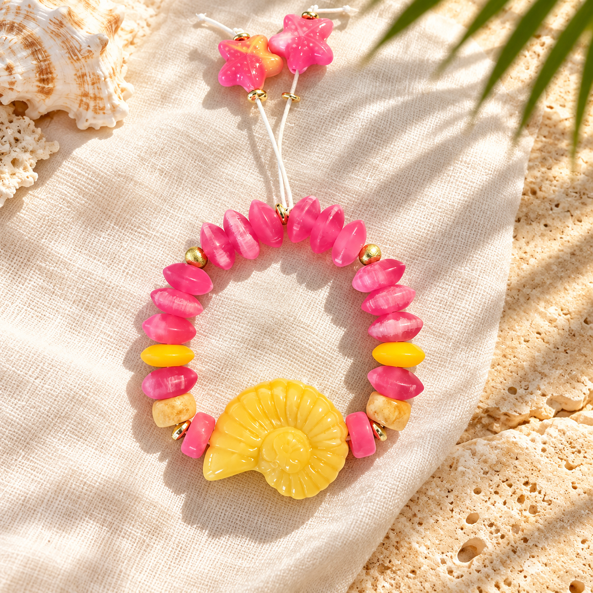 Pink beaded bracelet with yellow spiral shell and starfish cord ends