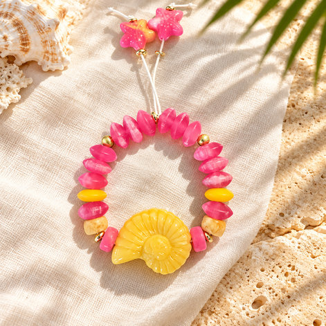 Pink beaded bracelet with yellow spiral shell and starfish cord ends